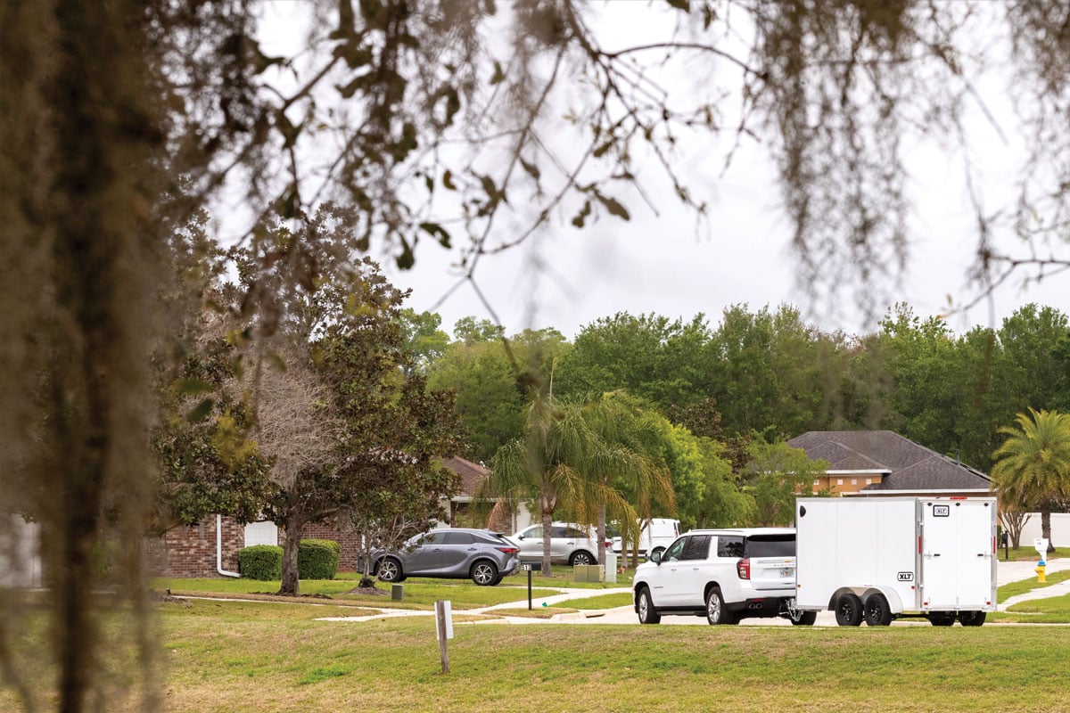 White SUV towing XLT Pro 7 Wide down neighborhood road
